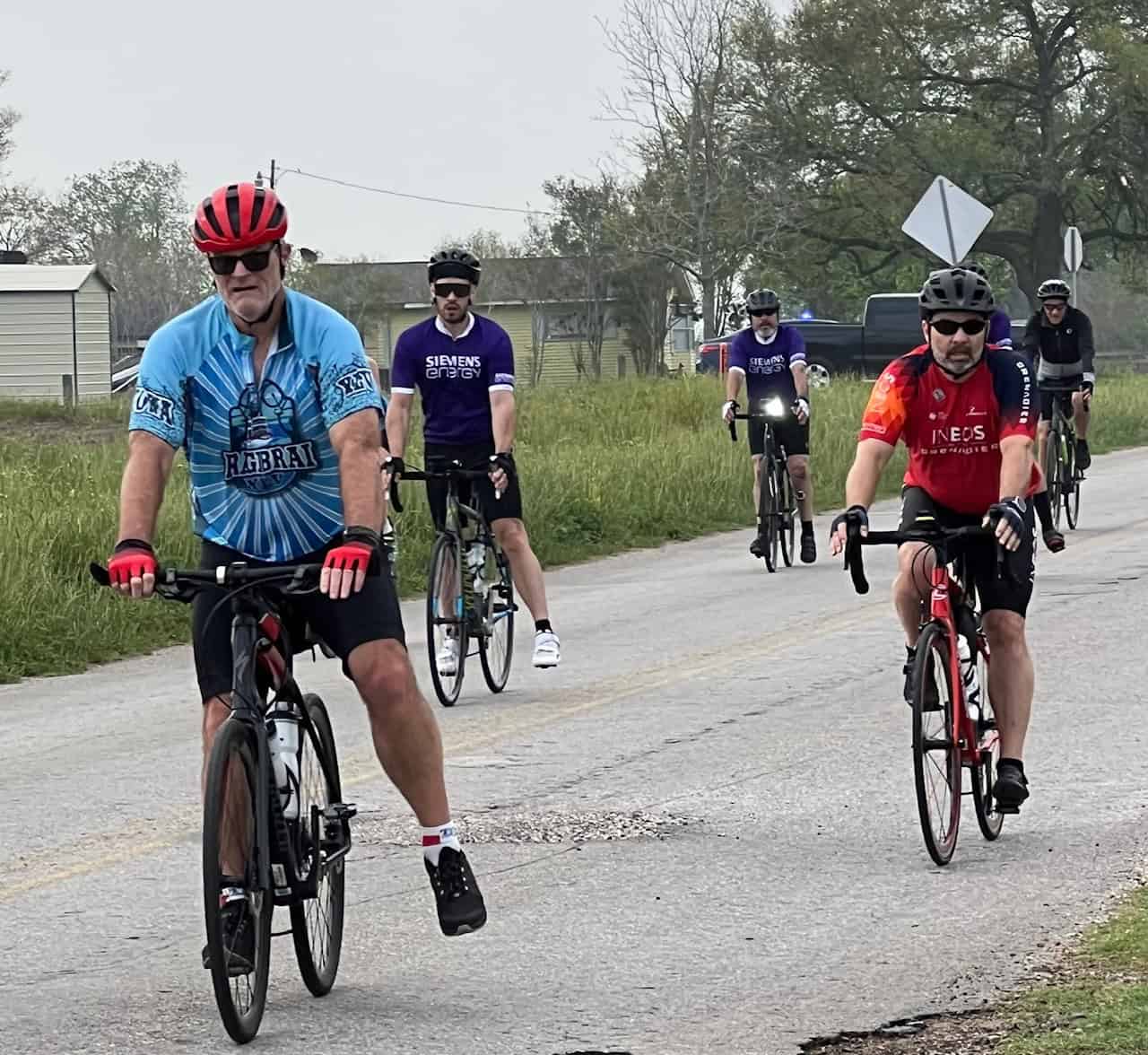 Bright blue and red cycling jerseys with riders on a local road enjoying a group bike ride.
